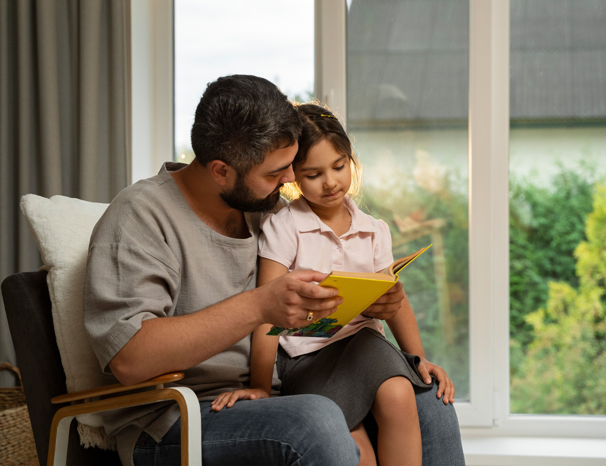 Father teaching something from book to his daughter
